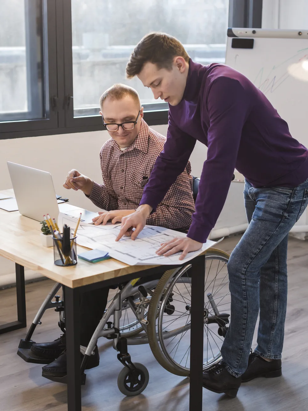 Colleague and wheelchair user reviewing documents together at an accessible desk