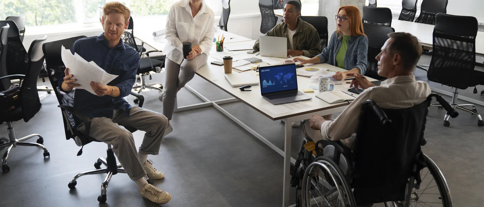 Inclusive open-plan office with a wheelchair user working alongside colleagues