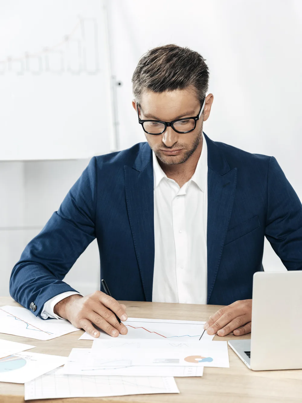 Consultant in a navy blazer reviewing printed audit results at his desk