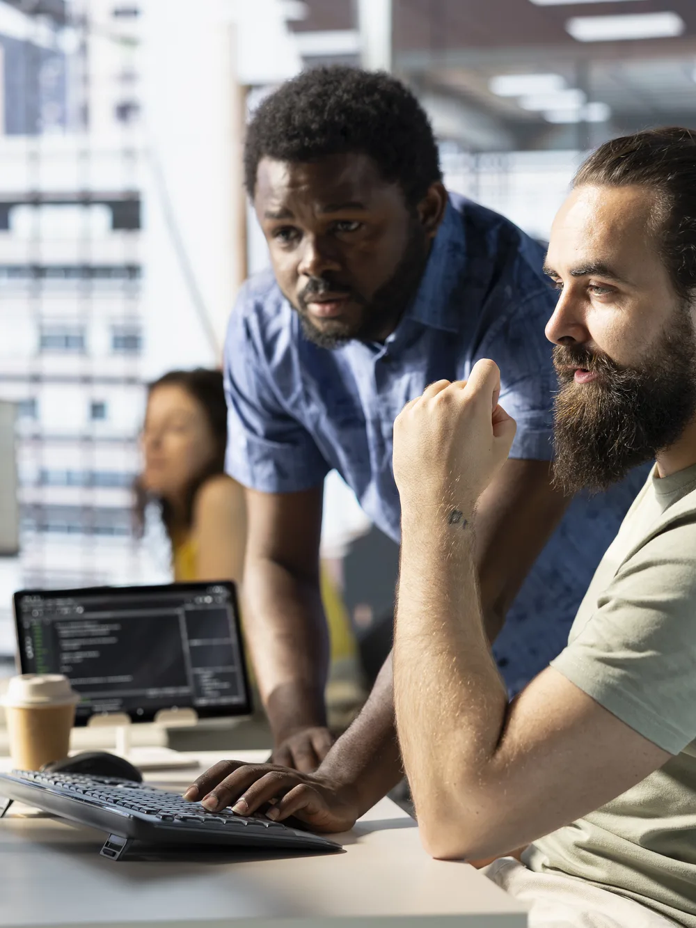 Two developers reviewing code together at a multi-monitor workstation