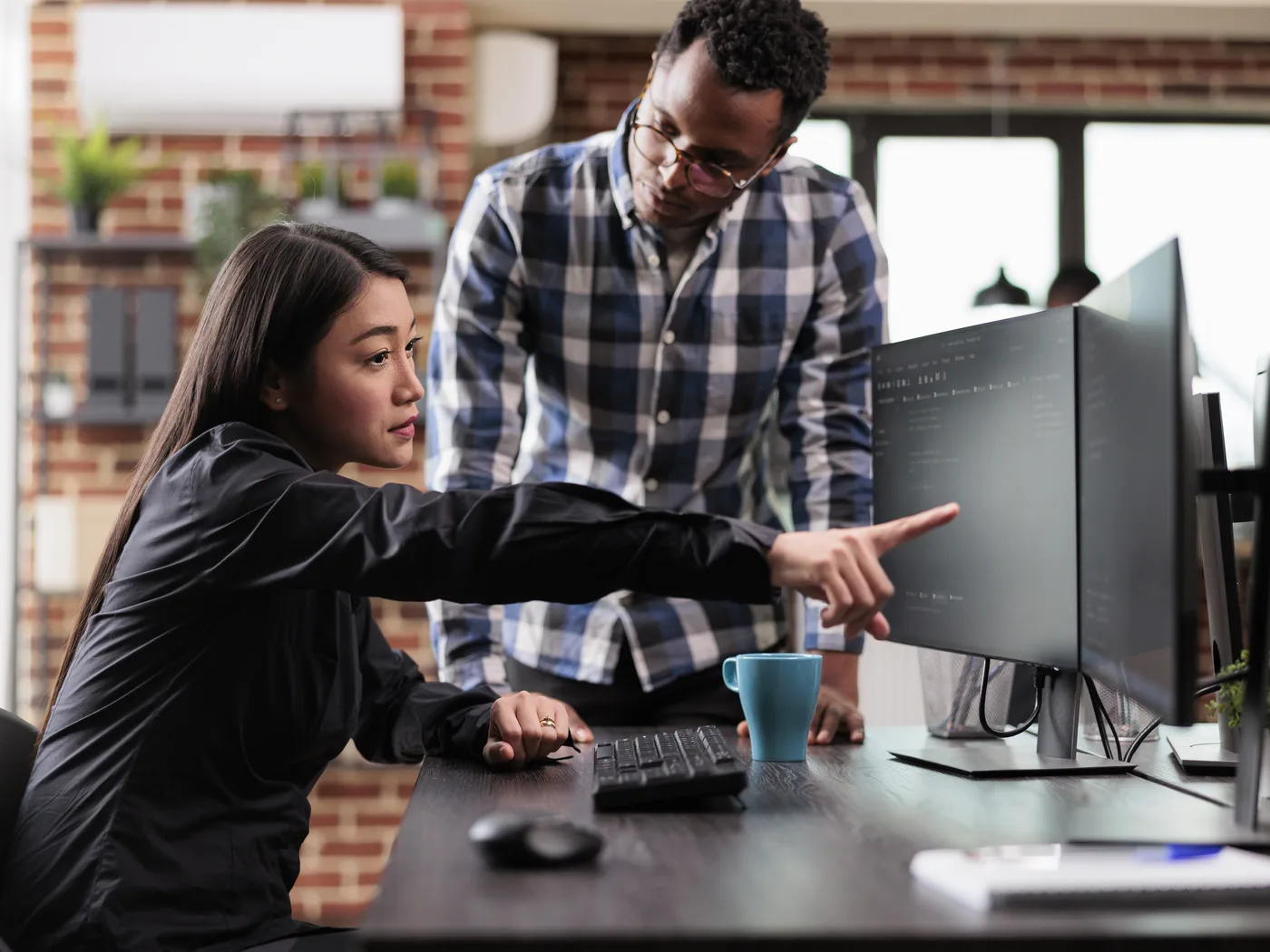Developer pointing out an error on screen to colleague