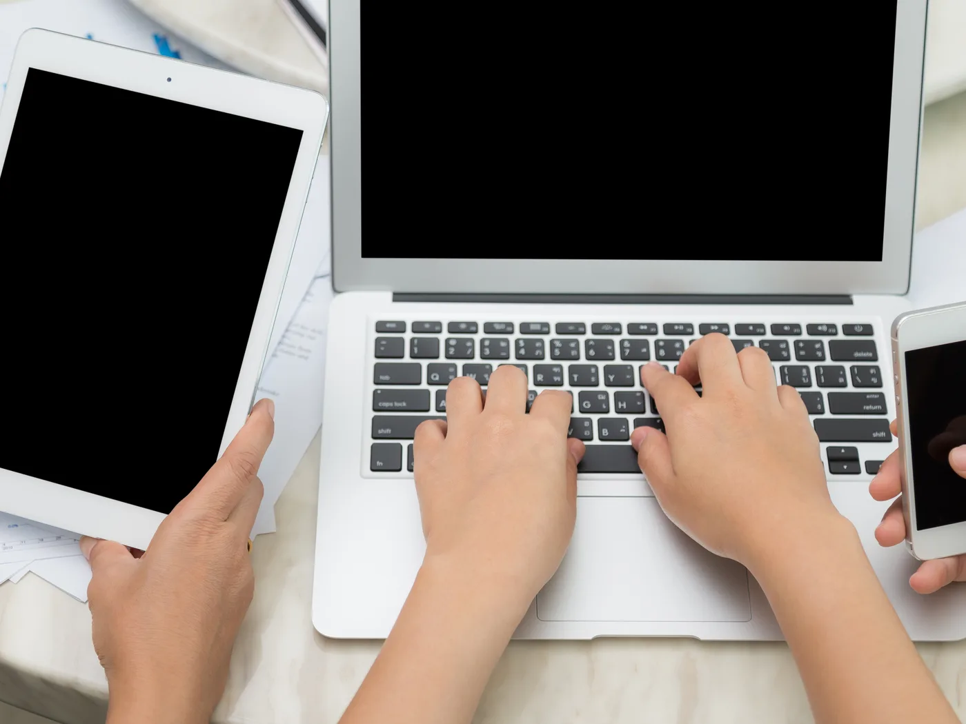 Hands using a tablet, laptop and smartphone together