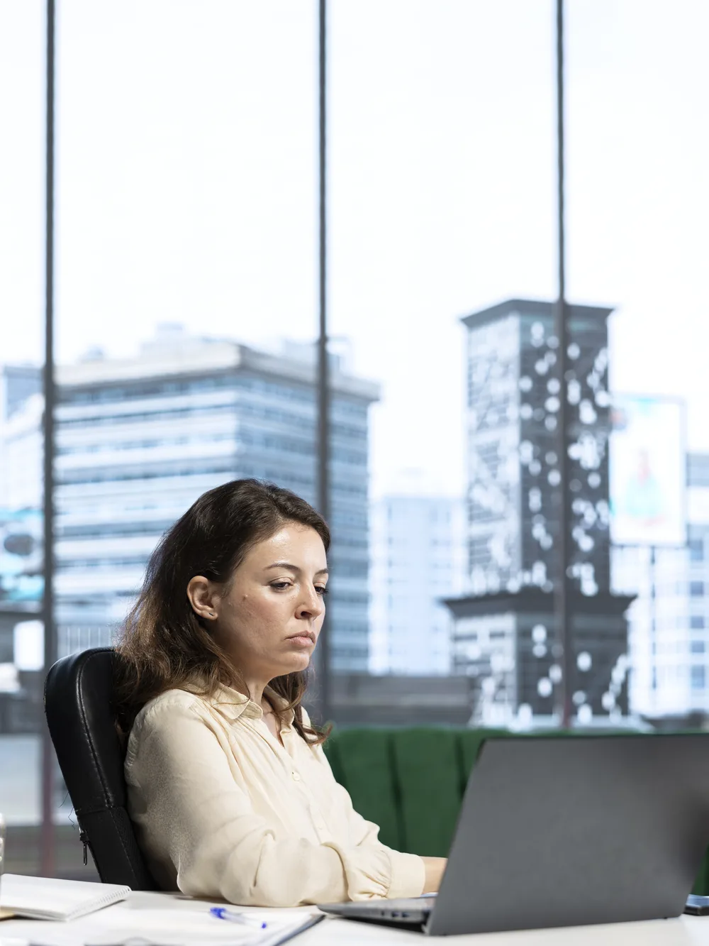Executive reviewing work on laptop in high-rise office