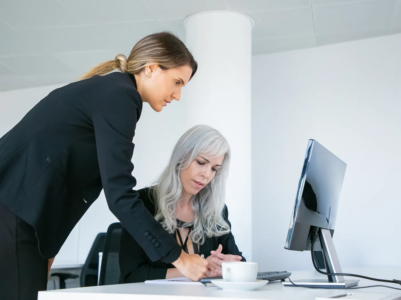 Two colleagues reviewing work together at a desktop