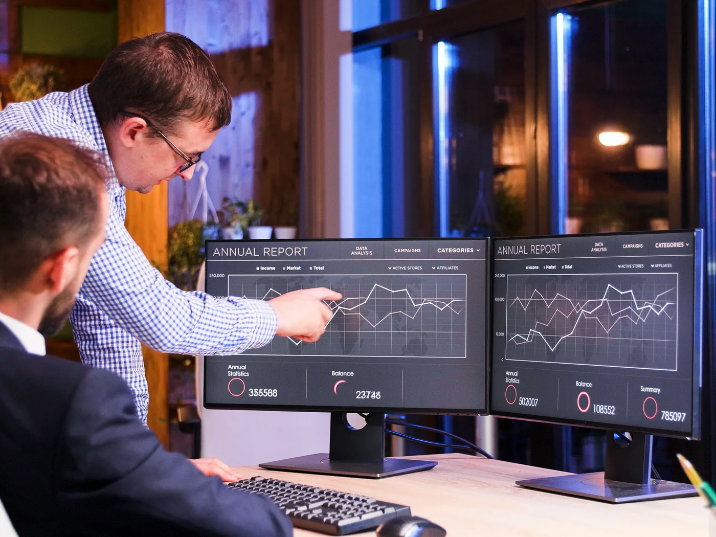 Two colleagues reviewing results on monitors at night