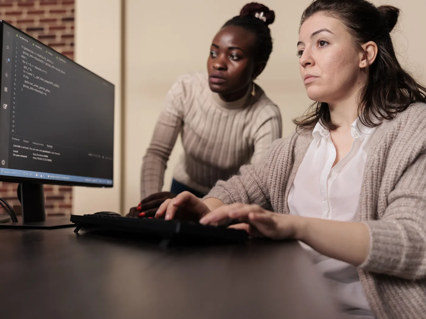 Two developers reviewing code on a monitor