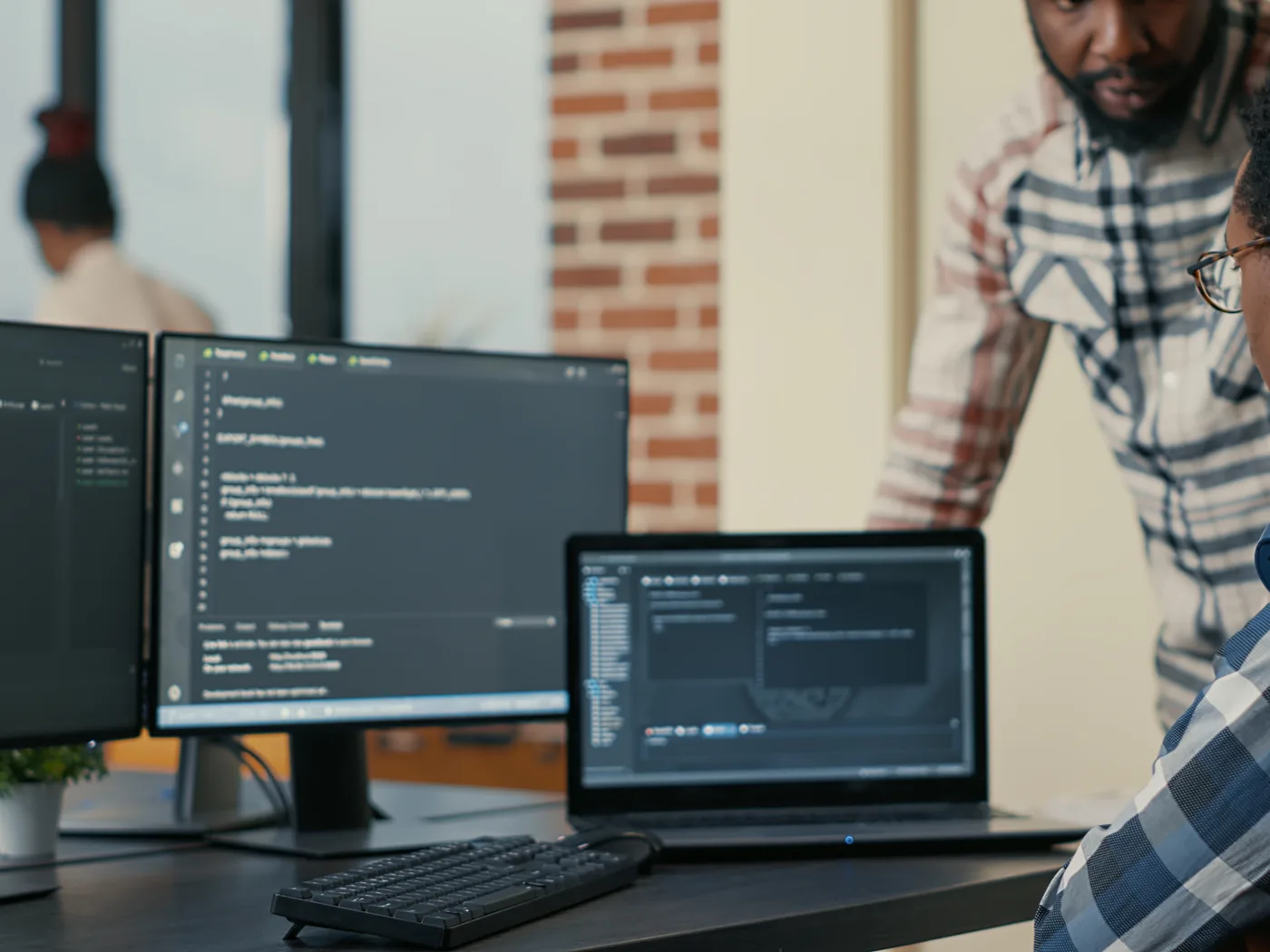 Developers discussing code shown on multiple screens