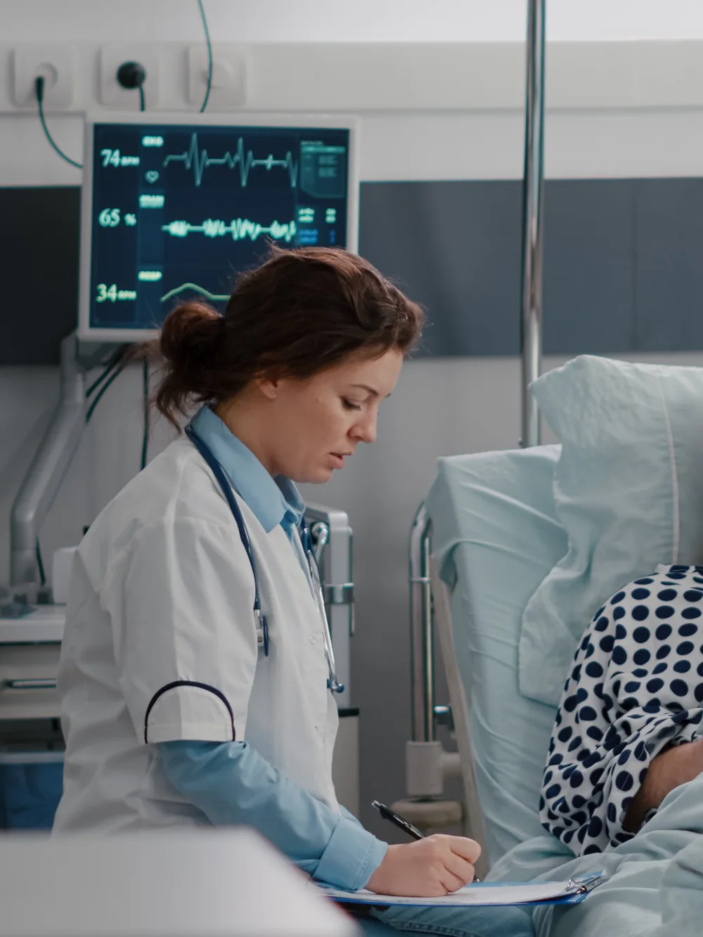 Nurse checking a patient at a ward bedside