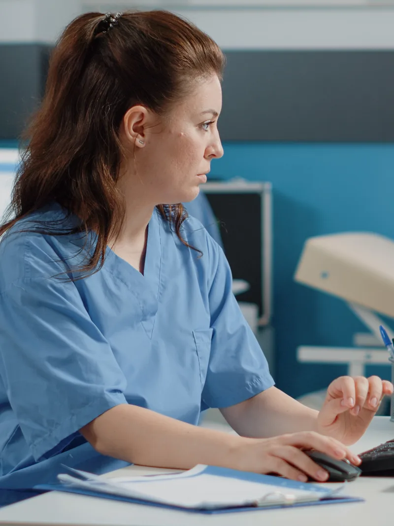 Nurse reviewing patient information on a desk computer