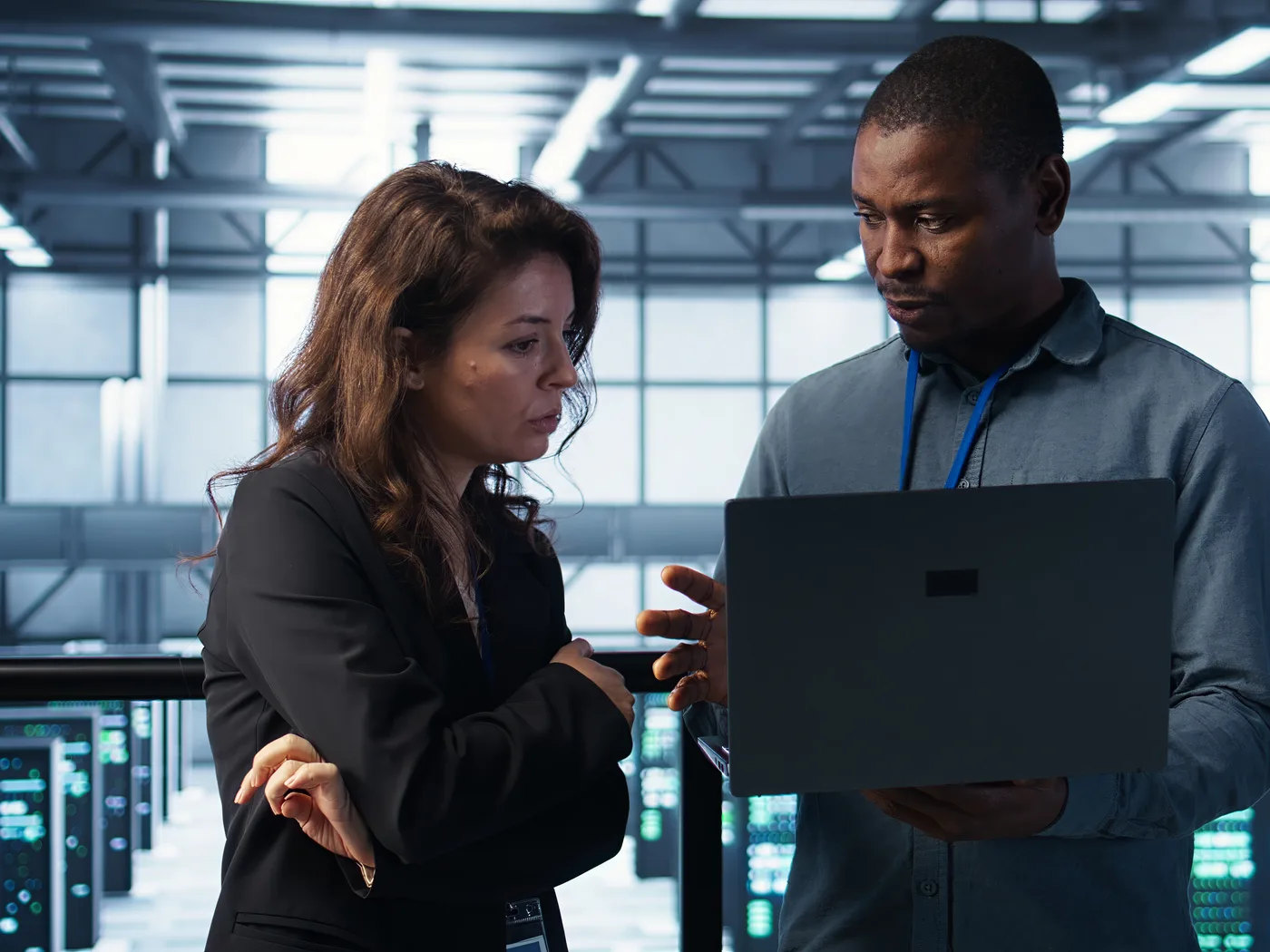 Two developers discussing a laptop in a data centre