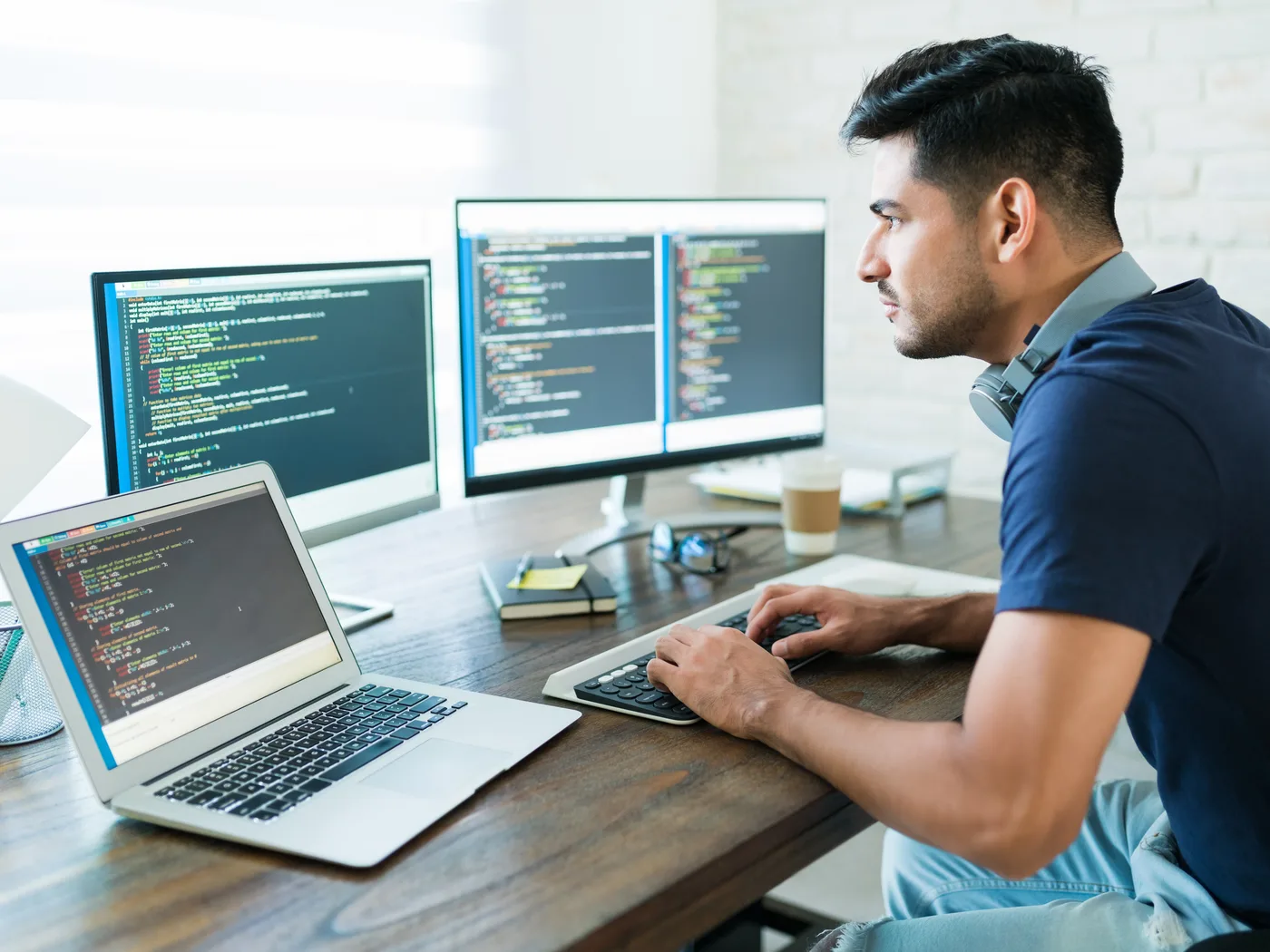 Developer coding across laptop and two monitors