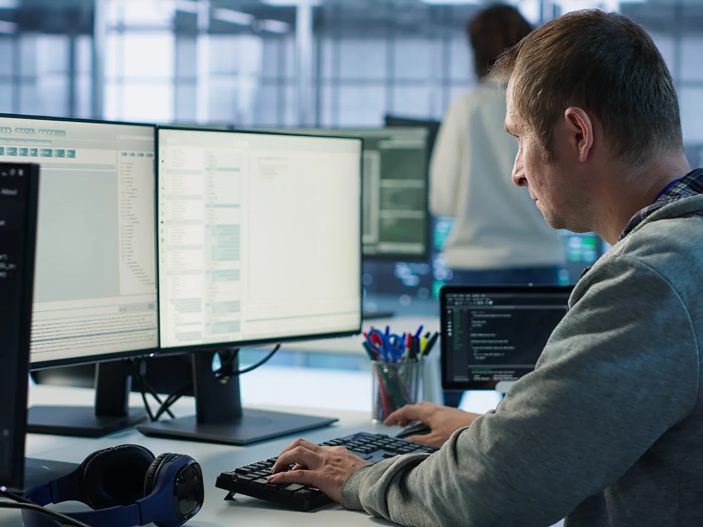 Programmer working on code across multiple monitors