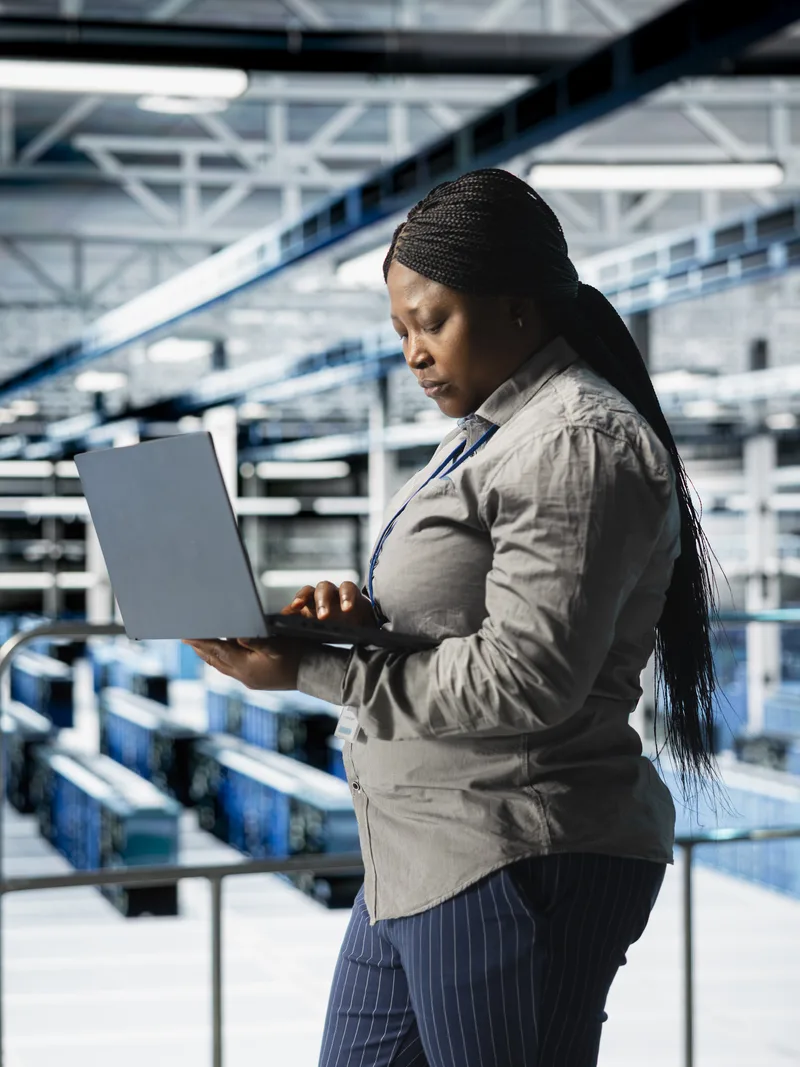 Engineer reviewing performance data on laptop in data centre