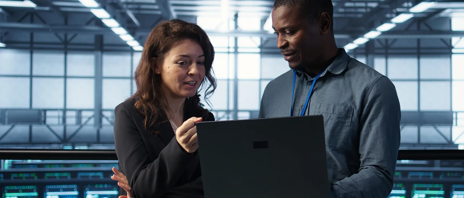 Two engineers discussing results on laptop in data centre