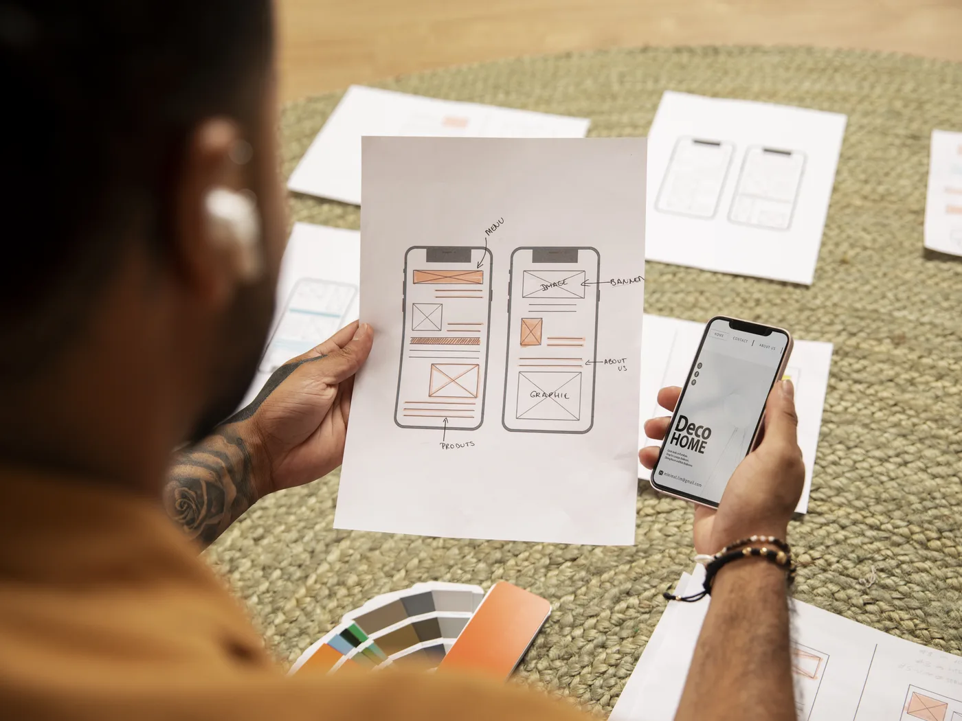Phone held beside printed app screen sketches