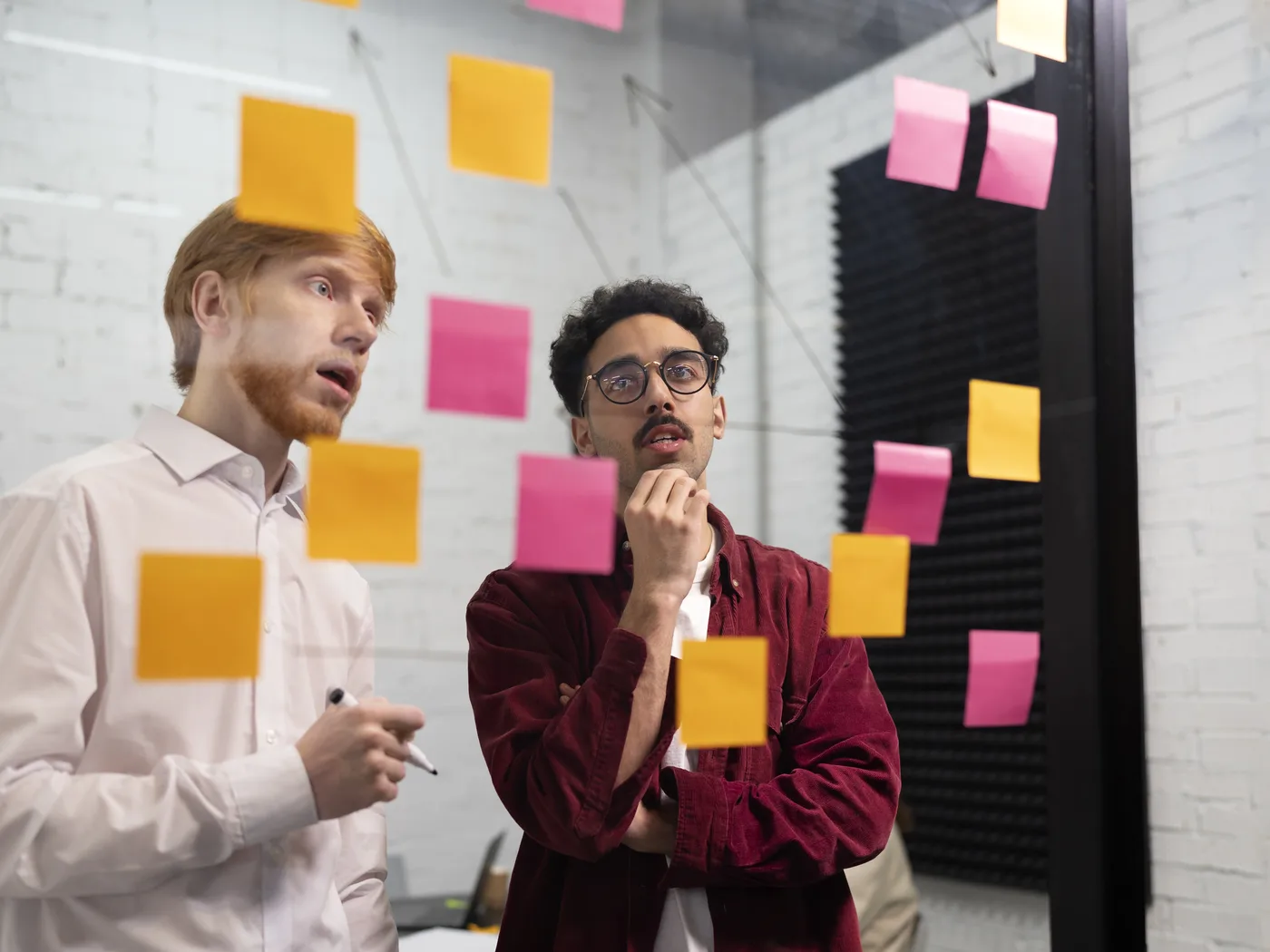 Two colleagues reviewing sticky notes on a planning wall