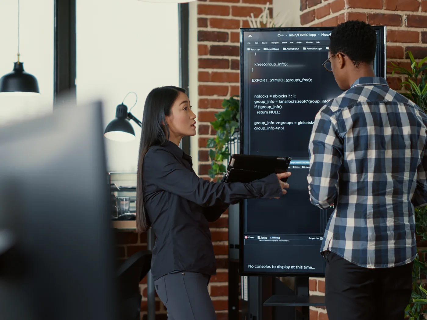 Developers reviewing code on a wall-mounted screen
