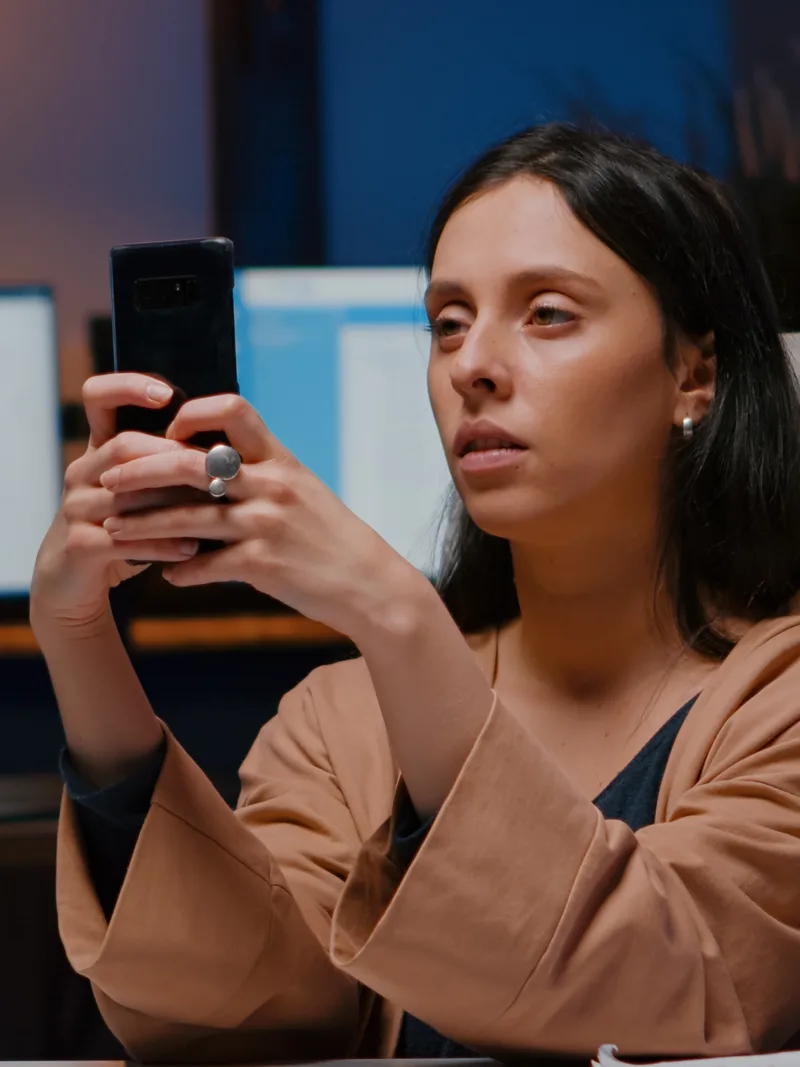 Frustrated woman checking her phone at an office desk