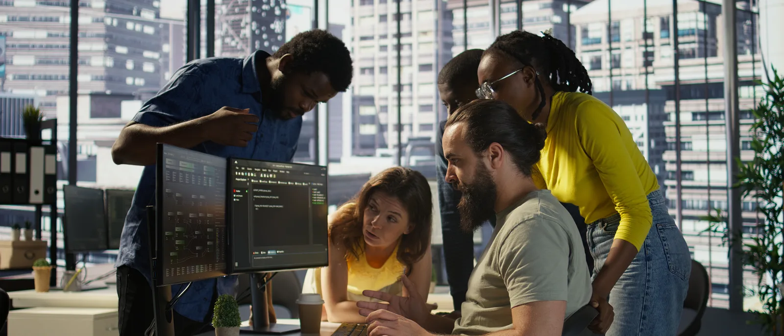 Developers gathered around monitors reviewing code in a bright open-plan office