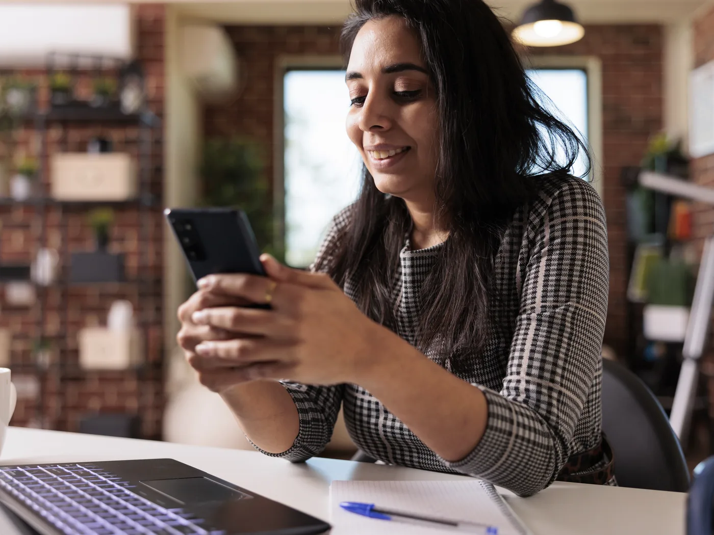 User checking an app on a smartphone beside a laptop