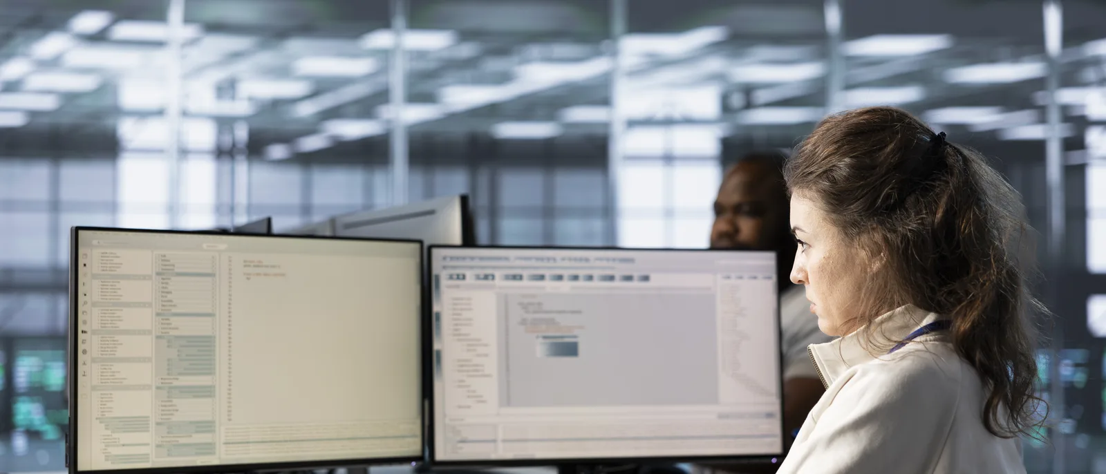 Engineer at dual monitors in a data centre operations room