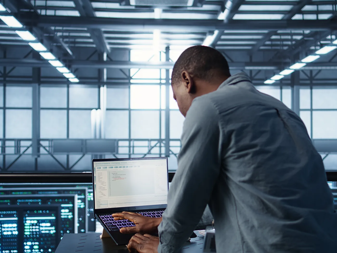 Engineer running a regression pack on a laptop in a data centre